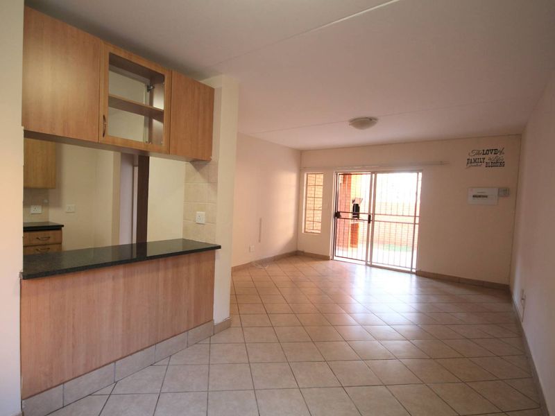 Open plan living area featuring tiled flooring, kitchen cabinetry with granite countertops, and a sliding glass door leading to an outdoor space.