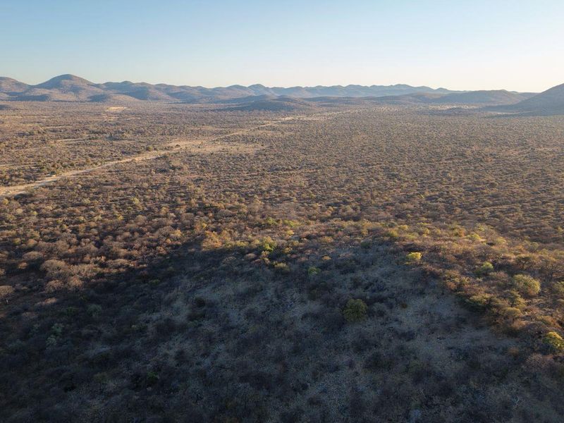 An expansive aerial view of the surrounding natural landscape, featuring rolling hills and vast bushveld terrain.