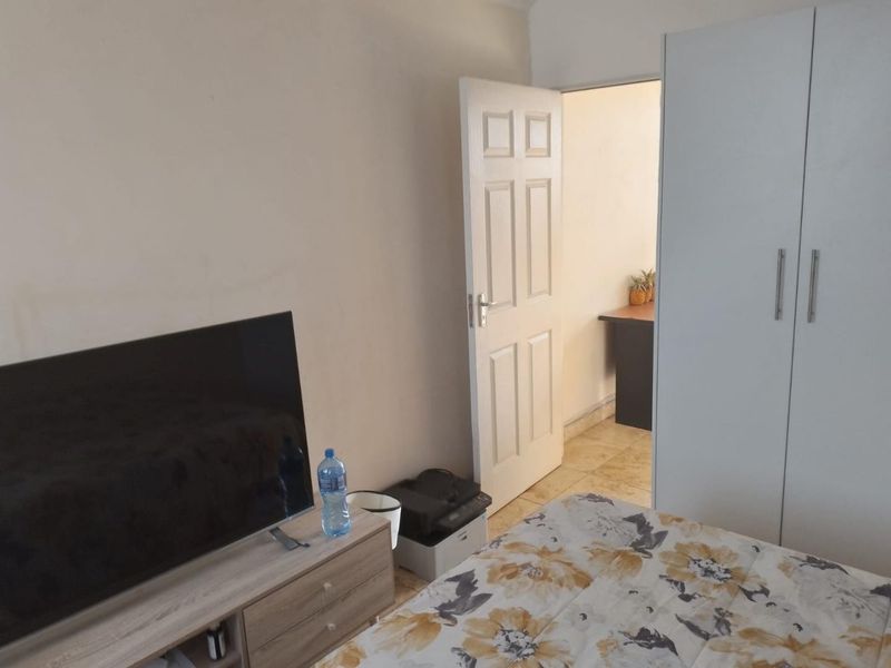 A bedroom featuring tiled flooring and a built-in wardrobe, with an open doorway leading to an adjacent space.