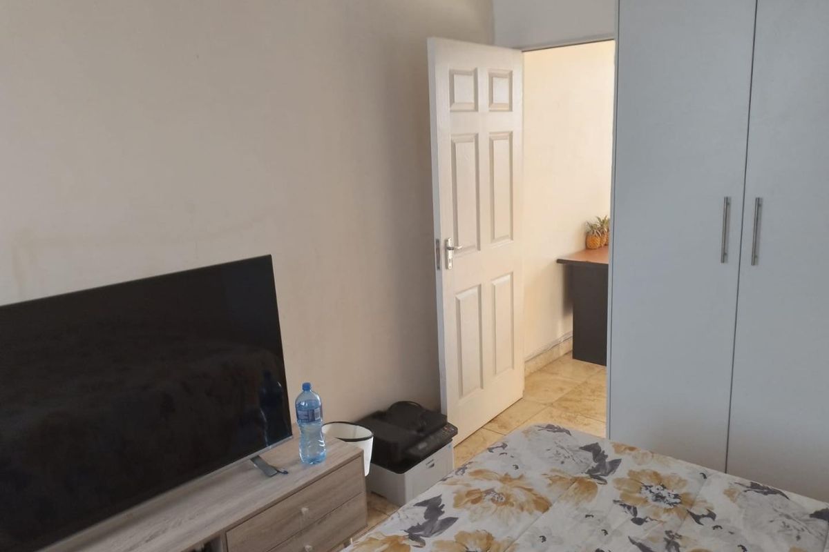 A bedroom featuring tiled flooring and a built-in wardrobe, with an open doorway leading to an adjacent space.