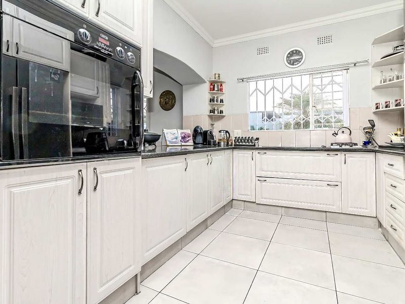 A well-maintained kitchen featuring white cabinetry, granite countertops, tiled flooring, and a built-in oven, offering a functional and classic workspace.