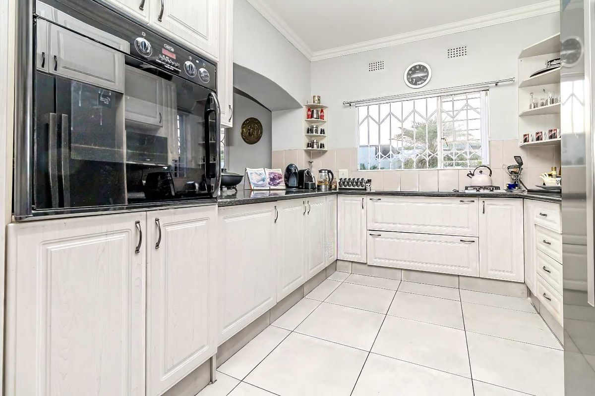 A well-maintained kitchen featuring white cabinetry, granite countertops, tiled flooring, and a built-in oven, offering a functional and classic workspace.