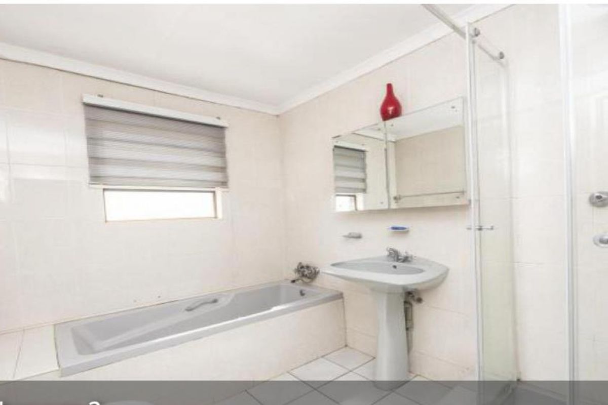 A functional bathroom featuring a built-in bathtub, pedestal basin, and a glass-enclosed shower with full-height wall tiling.