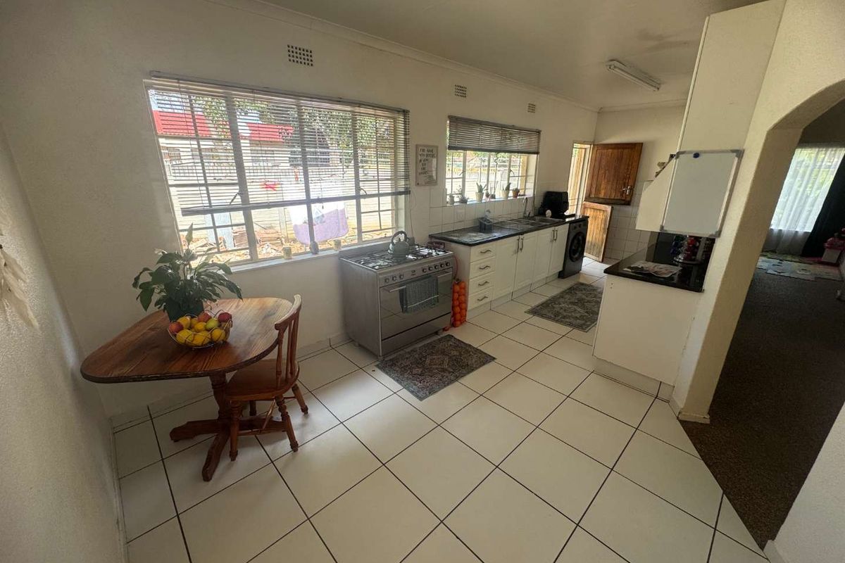 A functional kitchen featuring tiled flooring, built-in cabinetry, a stainless steel gas stove, and large windows providing natural light.