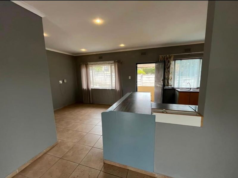 Open plan living area featuring tiled flooring, recessed lighting, and a functional kitchen space with a breakfast bar.