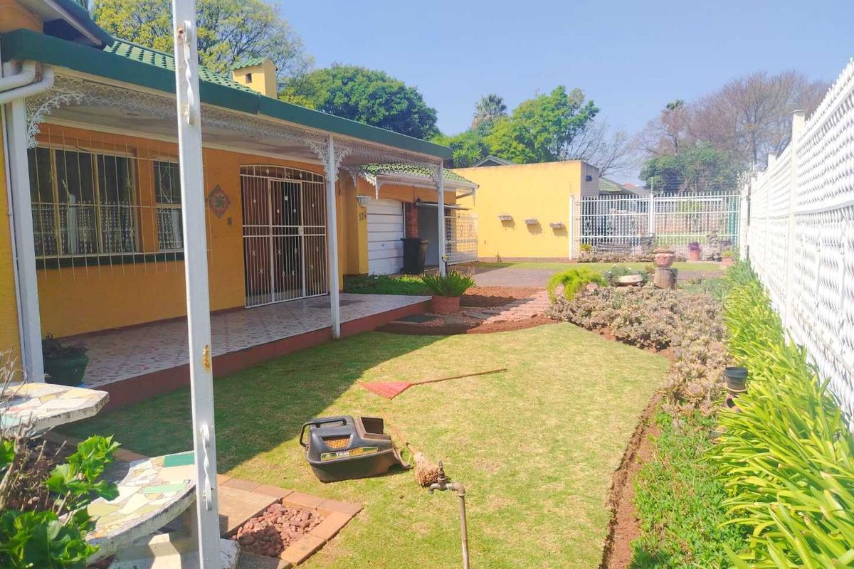 Rear view of the property featuring a covered patio, lawn area, and perimeter fencing, showing standard residential maintenance and exterior finishes.
