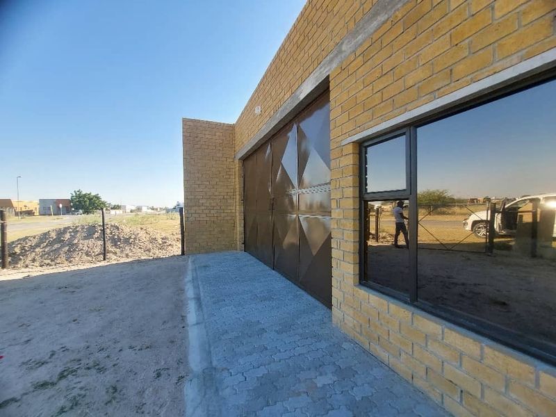 Exterior view of an industrial property featuring a face brick facade, large metal sliding door, and aluminium framed windows with a paved entrance area.