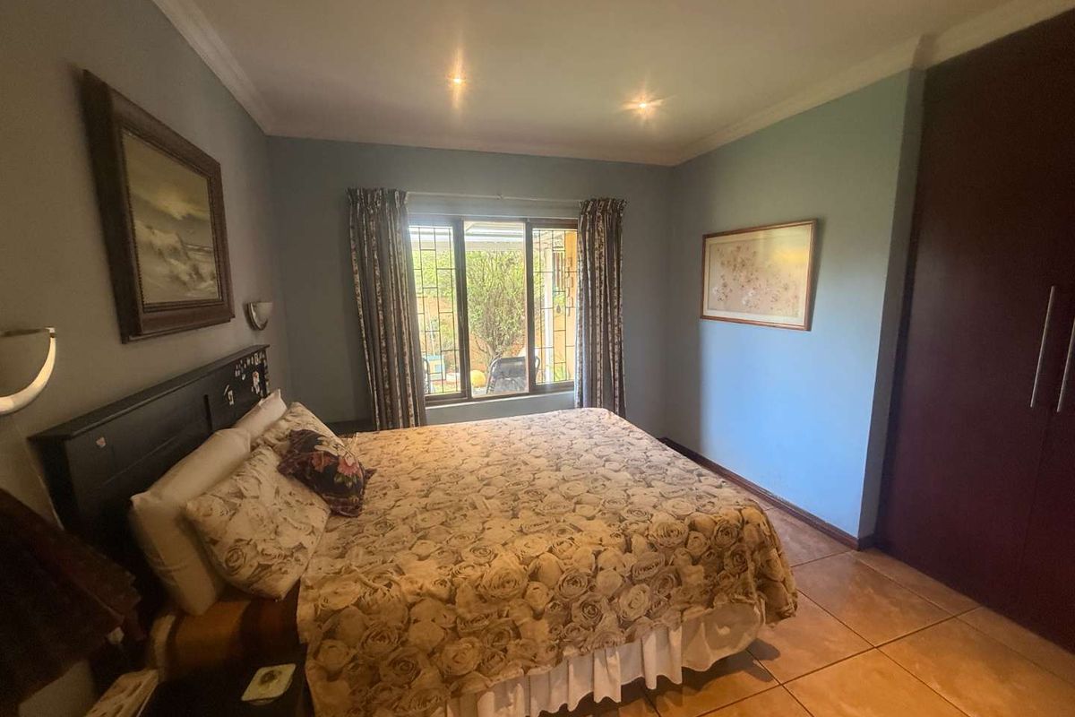 A bedroom featuring tiled flooring, built-in cupboards, recessed downlighting, and security bars on the window.