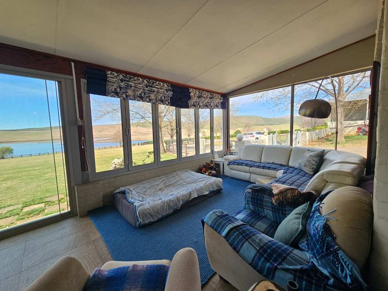 Enclosed patio area featuring extensive glass windows with scenic views of the surrounding farm landscape and lake.