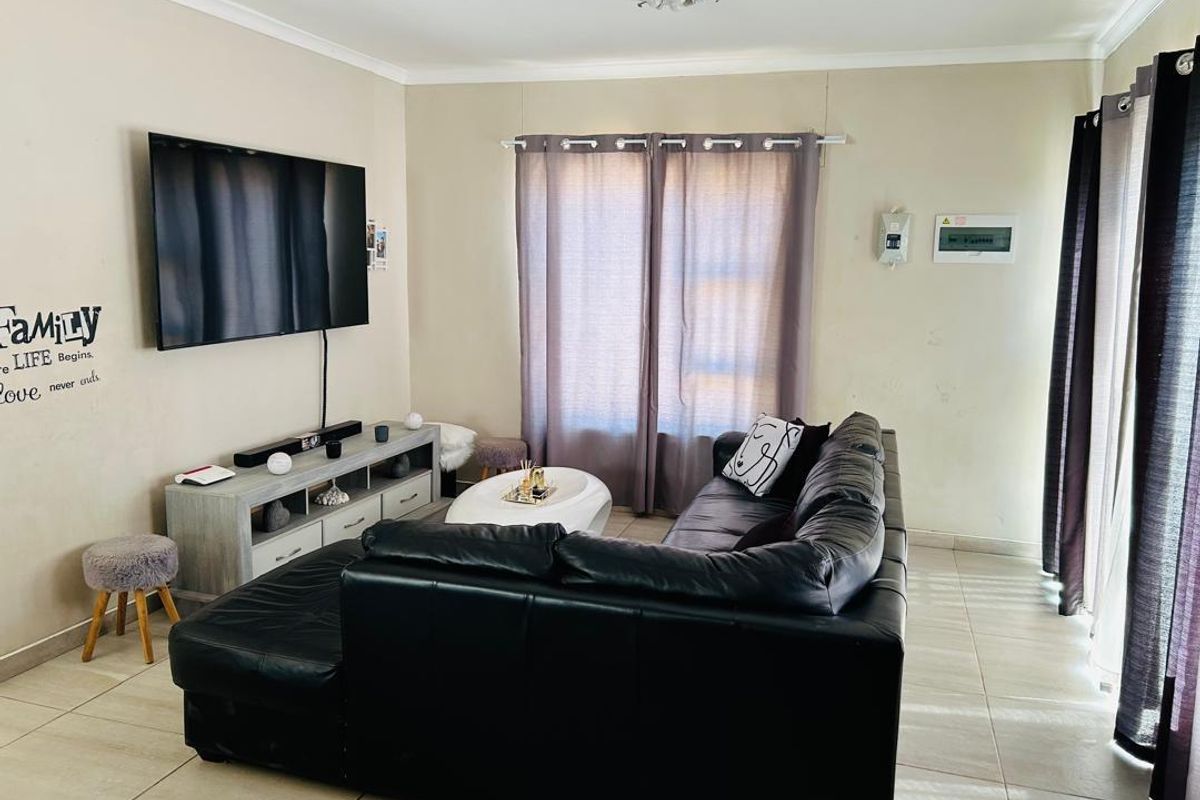 A functional living room featuring tiled flooring, neutral wall tones, and a sliding glass door providing natural light.
