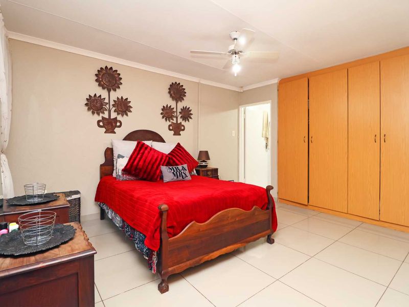 A bedroom featuring tiled flooring, a ceiling fan, and ample built-in cupboard storage space.
