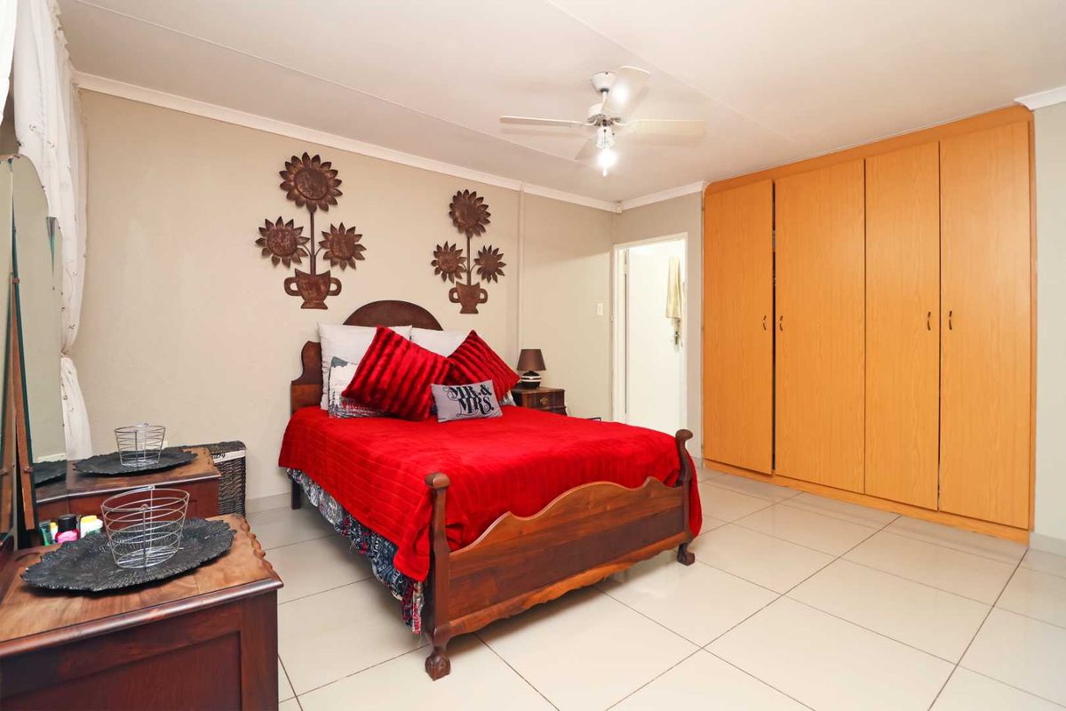A bedroom featuring tiled flooring, a ceiling fan, and ample built-in cupboard storage space.