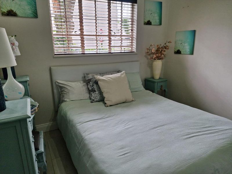 A cozy bedroom featuring a window with venetian blinds and neutral wall finishes.