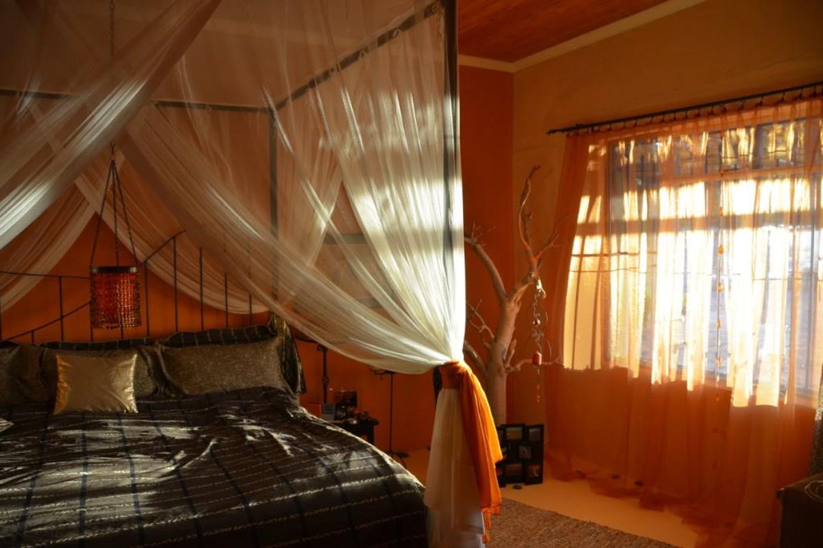 A bedroom featuring warm-toned walls, a wooden ceiling, and large windows that allow for natural light.