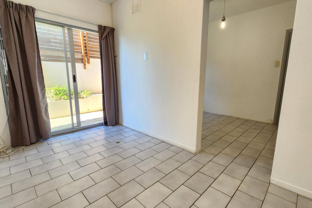 An empty living area featuring ceramic tile flooring and a sliding glass door providing access to an outdoor space.