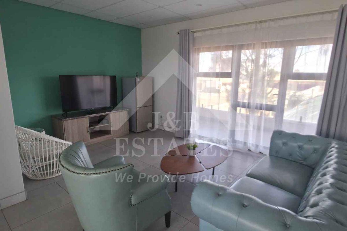 A comfortable living room featuring tiled flooring and a large sliding glass door that provides natural light and access to the exterior.