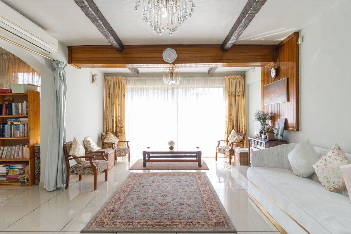 Spacious living room featuring tiled flooring, exposed timber ceiling beams, and large sliding glass doors providing ample natural light.