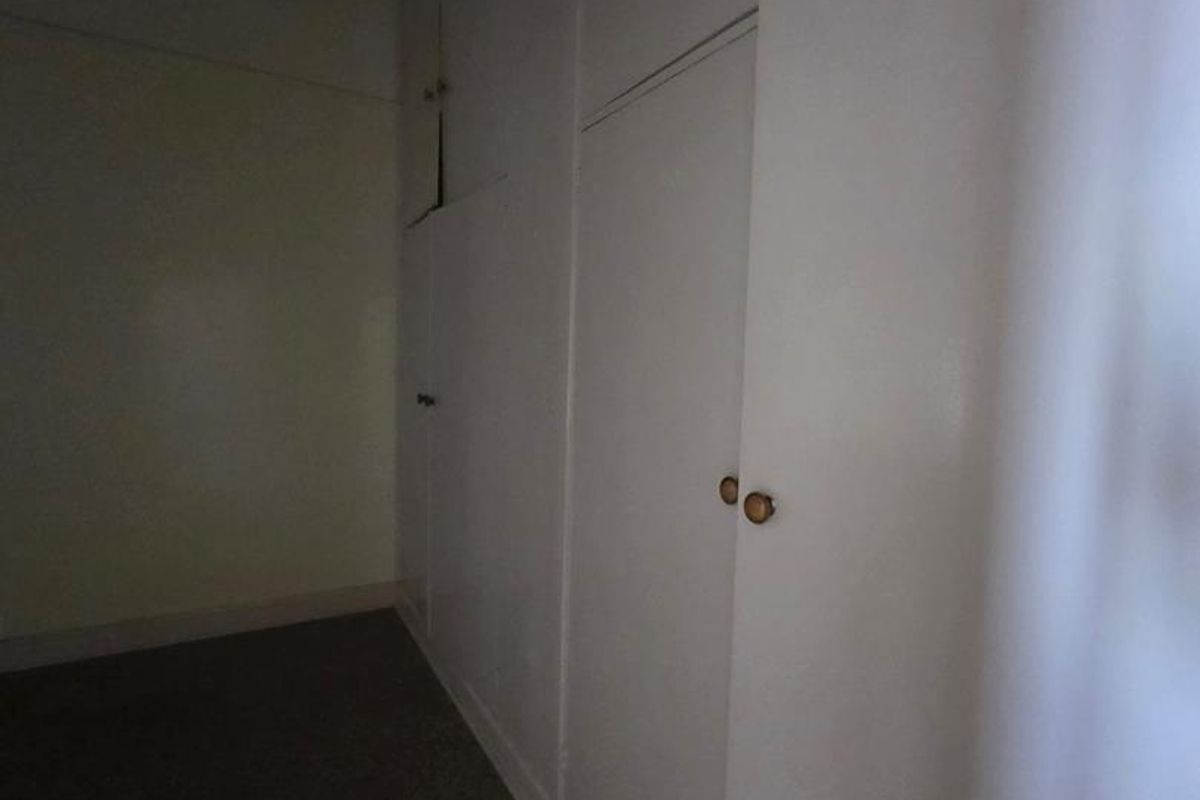 A bedroom featuring extensive built-in floor-to-ceiling storage cabinetry and carpeted flooring.