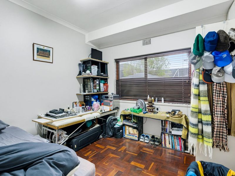 A bedroom featuring parquet flooring, a window with venetian blinds, and a ceiling vent.