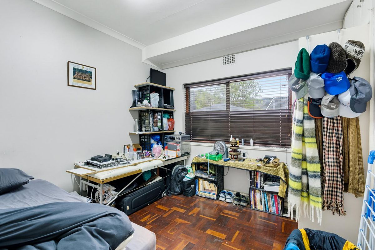 A bedroom featuring parquet flooring, a window with venetian blinds, and a ceiling vent.