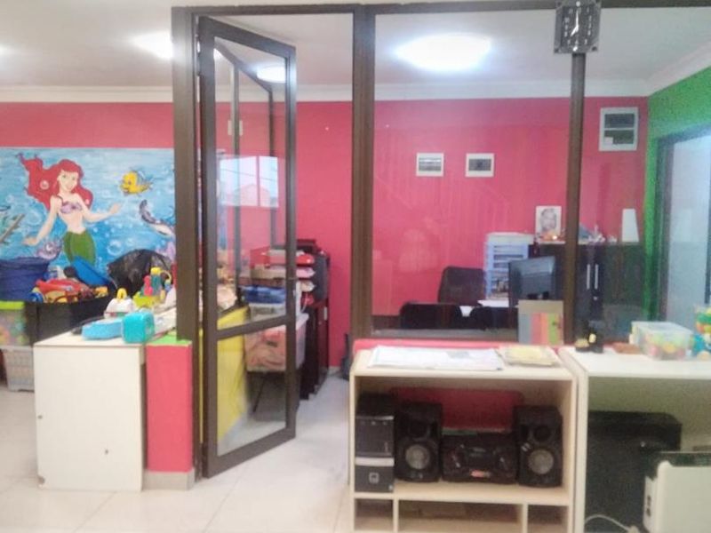 An interior office space featuring aluminium framed glass partitions, tiled flooring, and recessed lighting, currently decorated with vibrant wall murals.