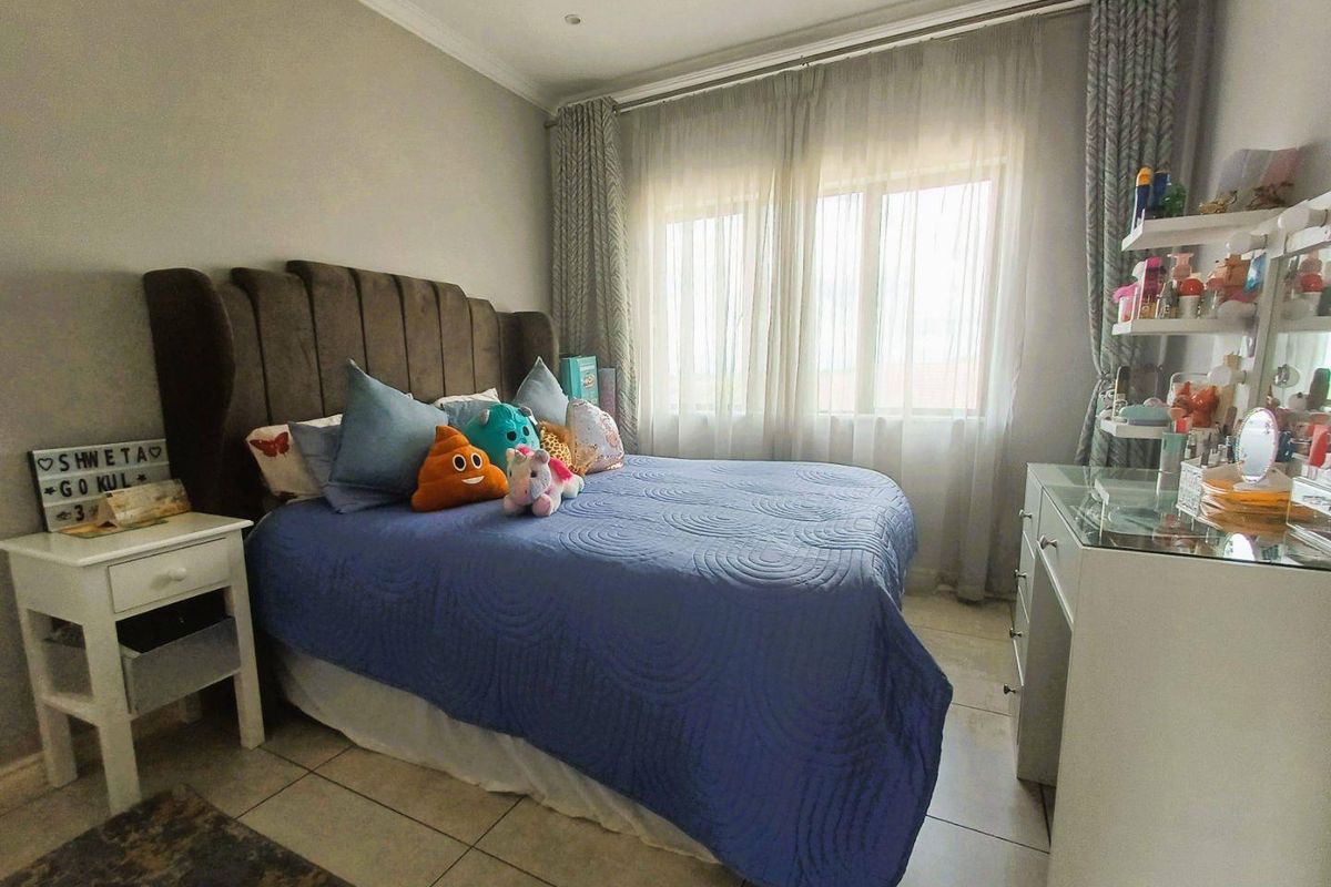 A well-maintained bedroom featuring tiled flooring, neutral wall tones, and large windows with curtain tracks, providing a comfortable and functional living space.