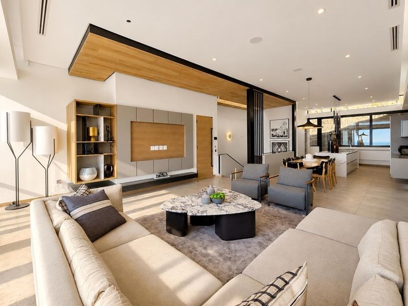 Spacious open-plan living and dining area featuring modern finishes, a built-in media wall, timber ceiling accents, and a sleek kitchen with a central island.