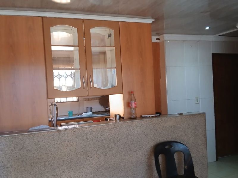 A kitchen area featuring wooden cabinetry, granite countertops, and a tiled splashback, offering a functional layout with potential for modern updates.