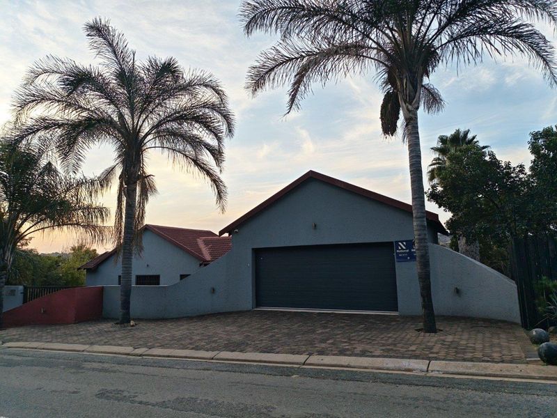 Front exterior view of the property featuring a paved driveway, a secure garage, and established palm trees.