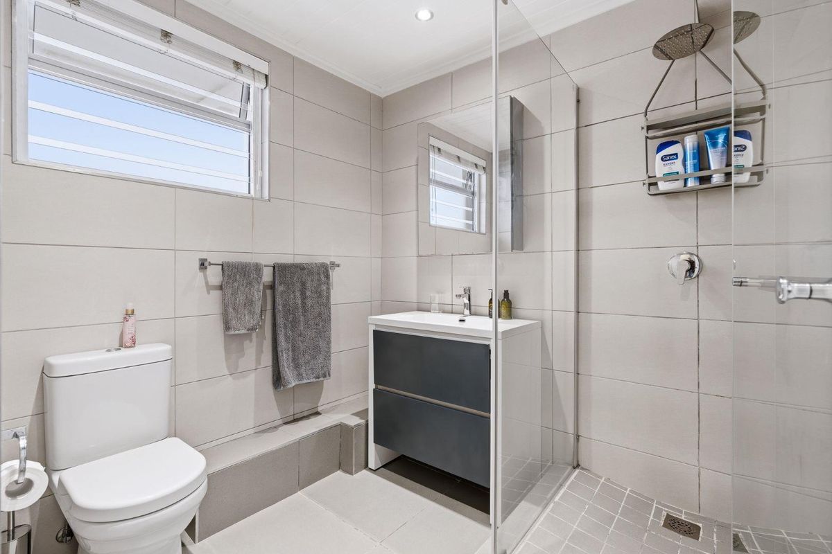 Modern bathroom featuring a glass-enclosed walk-in shower, contemporary vanity unit, and neutral wall tiling.