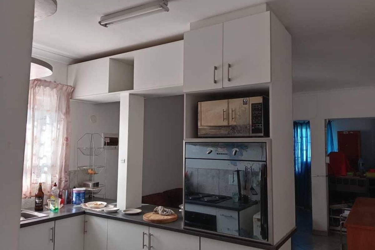 Functional kitchen featuring white built-in cabinetry, laminate countertops, and integrated oven and microwave appliances.