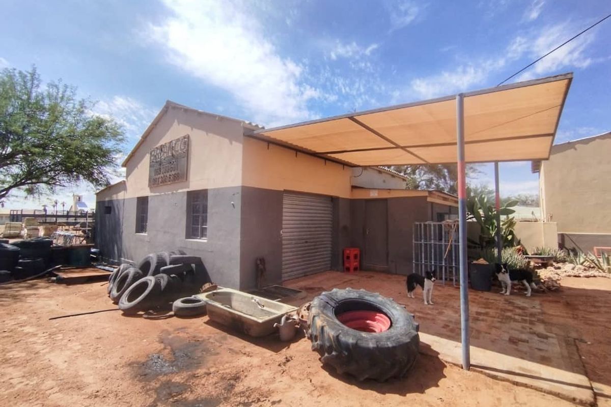 Exterior view of a commercial building featuring a covered patio area, roller shutter door, and basic masonry construction.