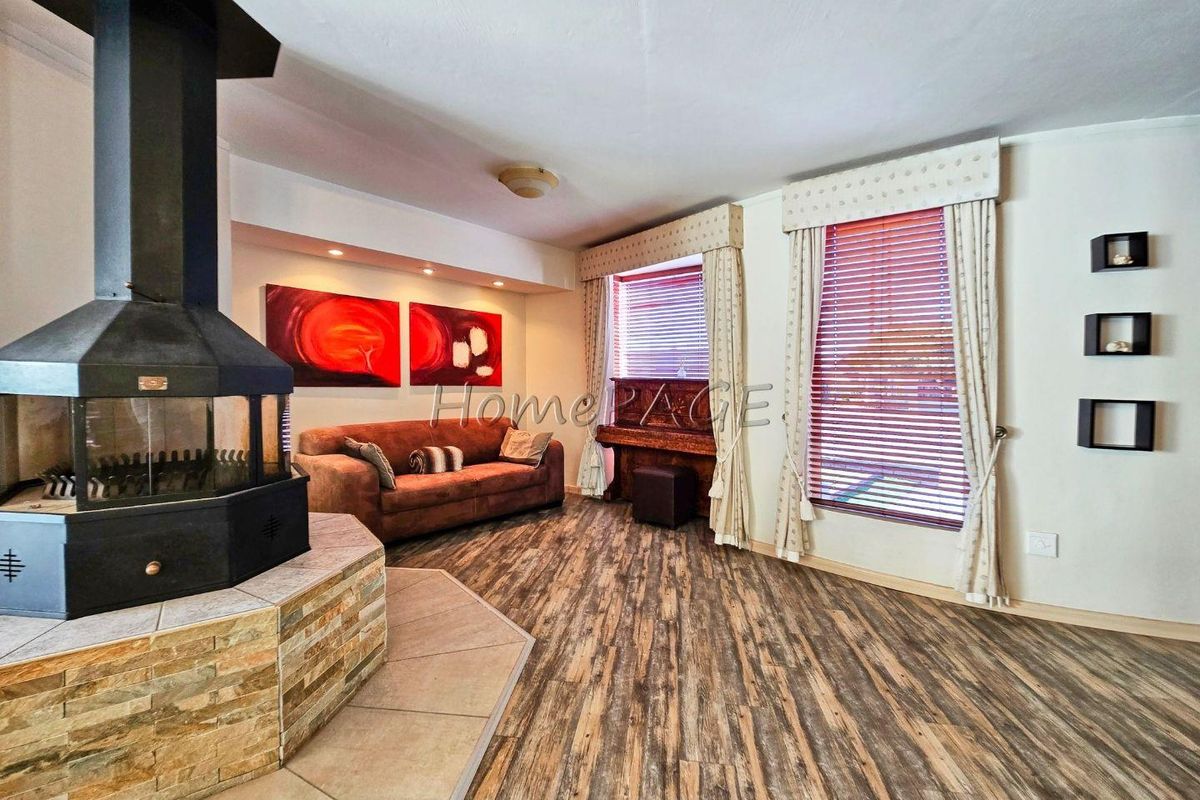 Spacious living room featuring a prominent central fireplace with stone cladding and wood-look laminate flooring.