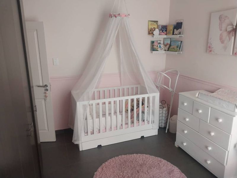 A nursery bedroom featuring pink wainscoting and dark tiled flooring.