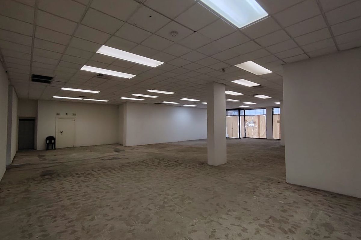 Spacious open-plan retail unit featuring a suspended ceiling, recessed lighting, and large display windows, offering a blank canvas for commercial customization.