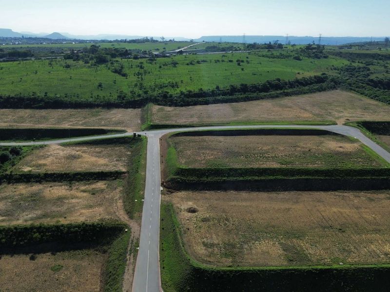 Aerial view of an industrial development site featuring paved access roads and prepared, terraced land plots ready for construction.