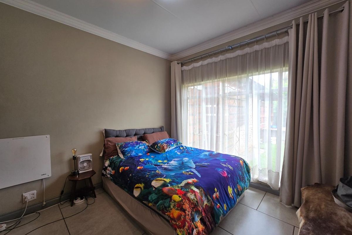 A bedroom featuring tiled flooring, crown molding, and a large window with curtain tracks, providing natural light.