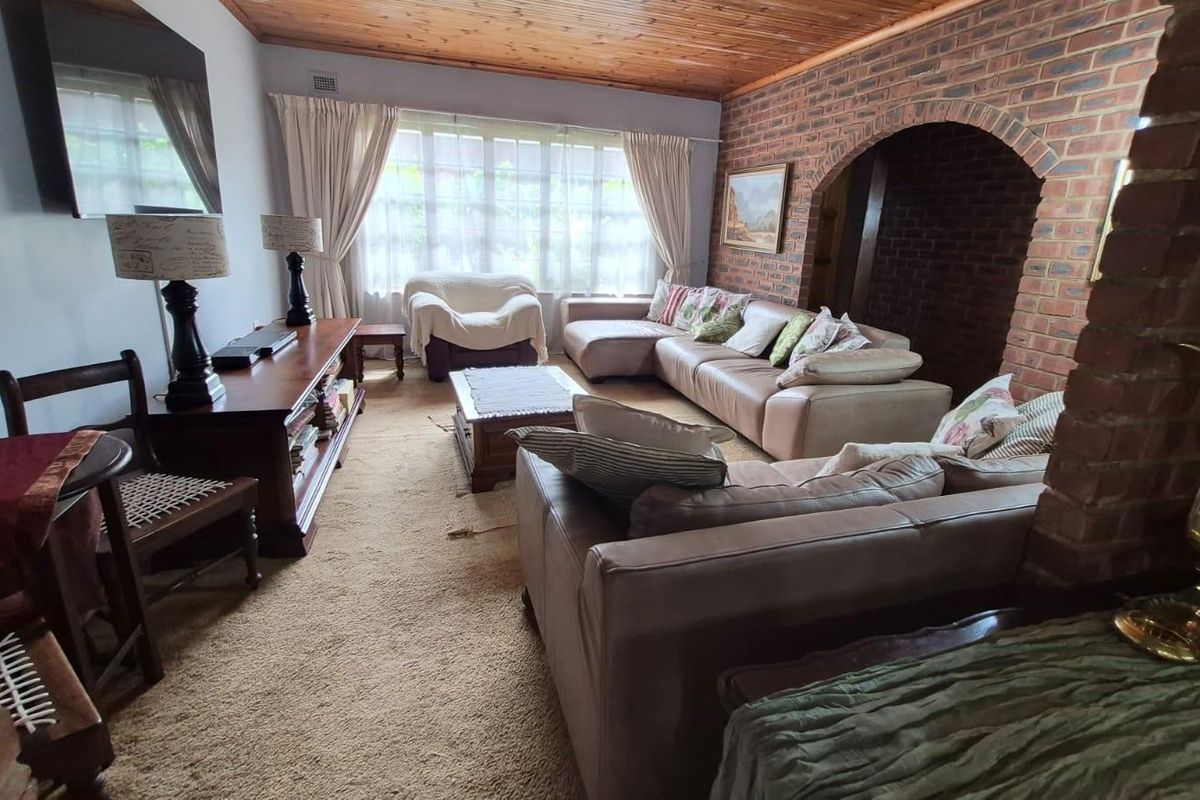 Spacious living room featuring a rustic exposed brick wall, a warm timber-paneled ceiling, and a distinctive brick archway leading to adjacent areas.