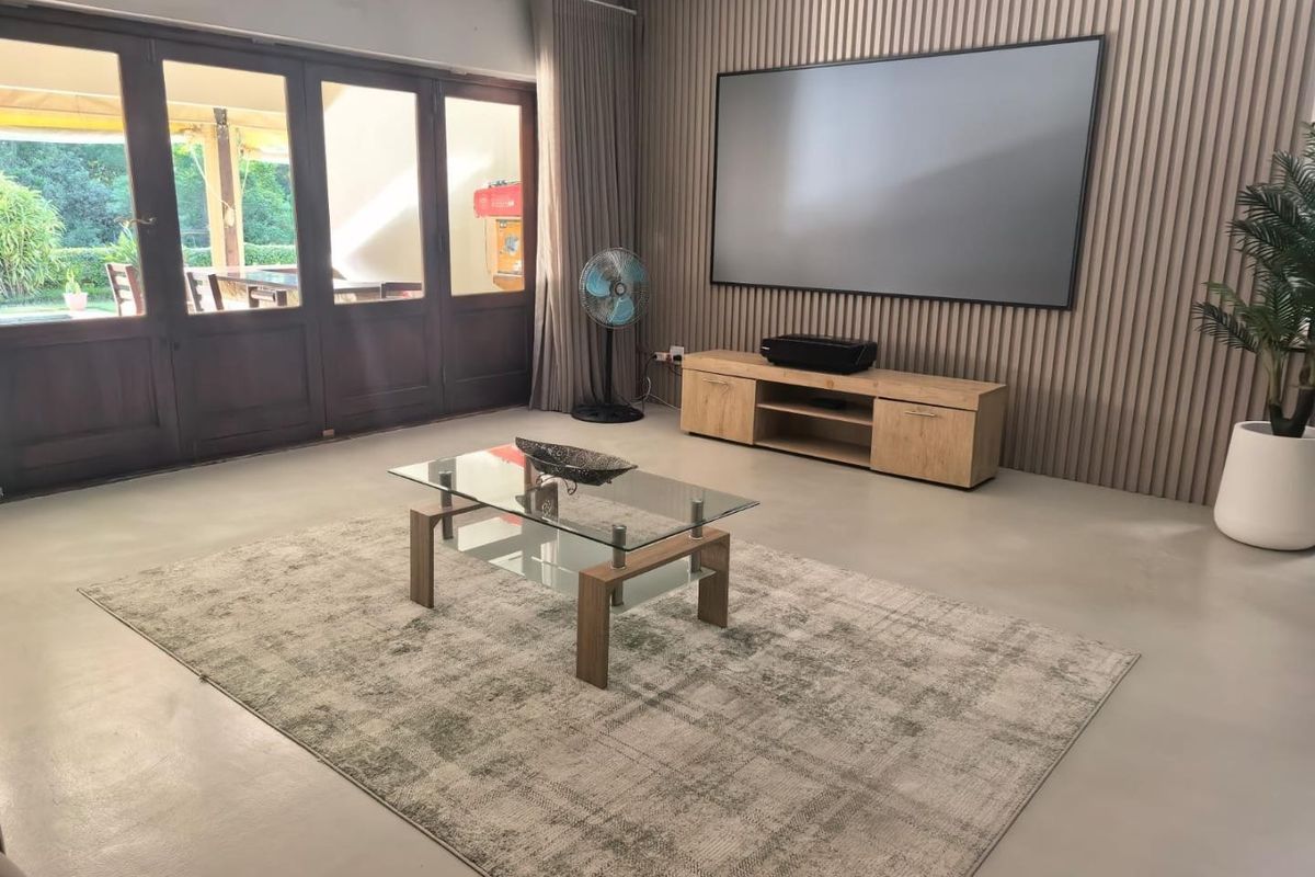 Spacious living room featuring modern timber slat wall paneling, polished concrete floors, and large timber-framed glass doors providing seamless access to the outdoor patio area.