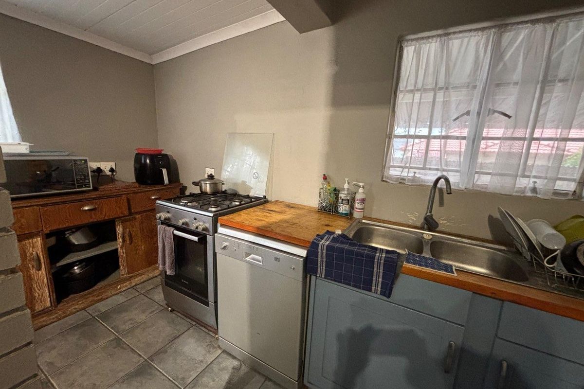 A functional kitchen featuring a gas stove, timber countertops, double bowl sink, and tiled flooring, offering potential for a modern renovation.