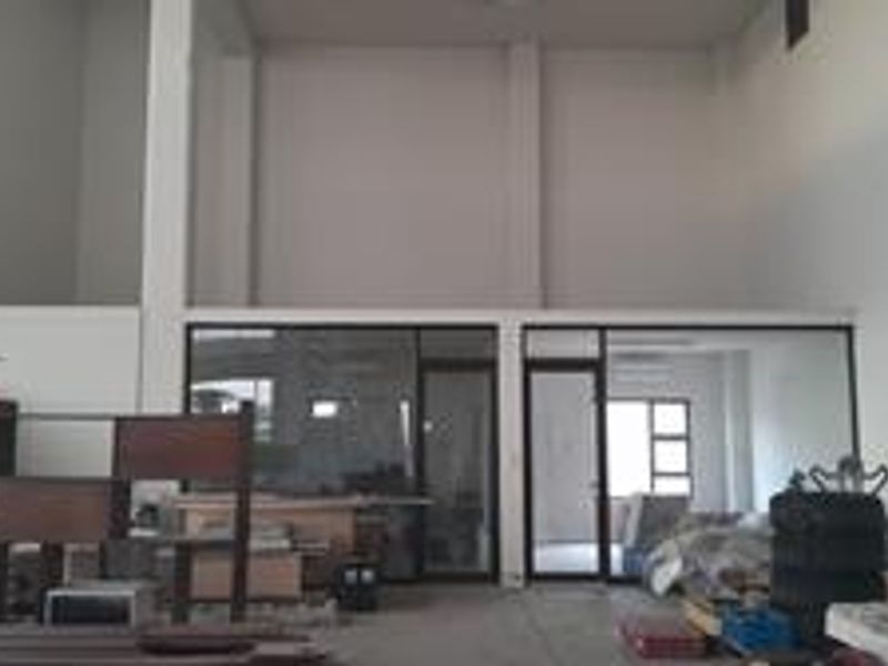 Spacious industrial utility area featuring high ceilings, a mezzanine level, and aluminum-framed glass partitions, offering a versatile open-plan layout.