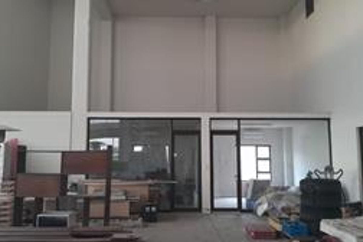 Spacious industrial utility area featuring high ceilings, a mezzanine level, and aluminum-framed glass partitions, offering a versatile open-plan layout.
