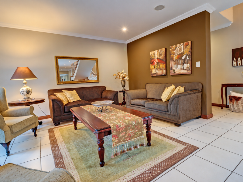 A well-maintained living room featuring neutral wall tones, a contrasting feature wall, and ceramic tiled flooring with recessed lighting.