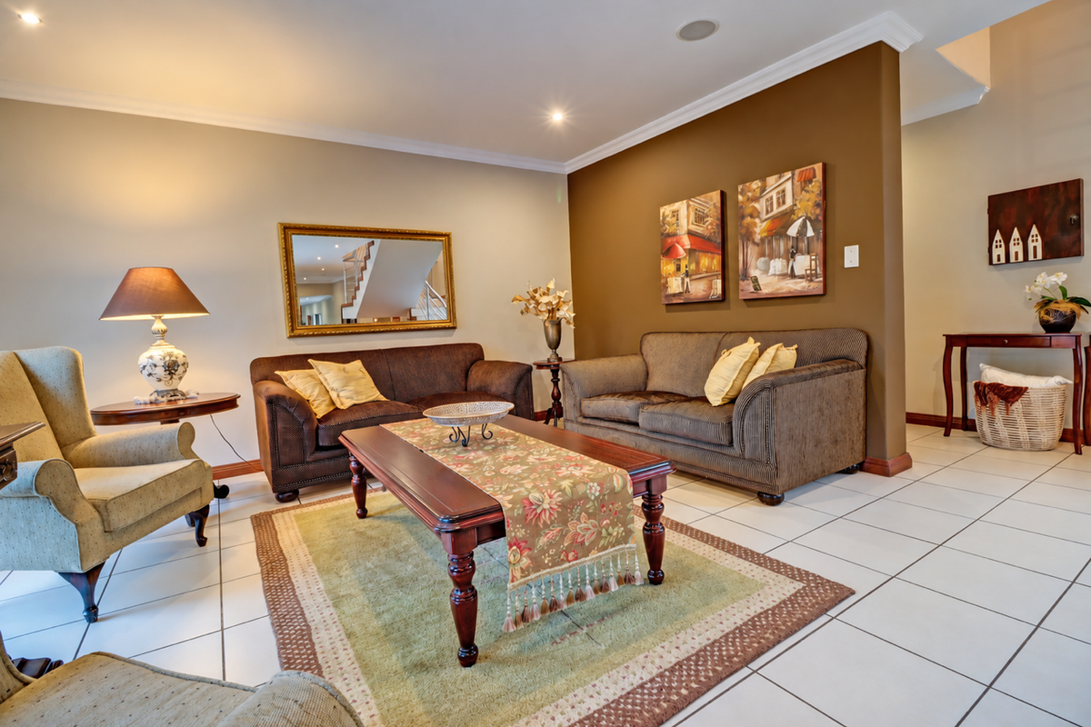 A well-maintained living room featuring neutral wall tones, a contrasting feature wall, and ceramic tiled flooring with recessed lighting.