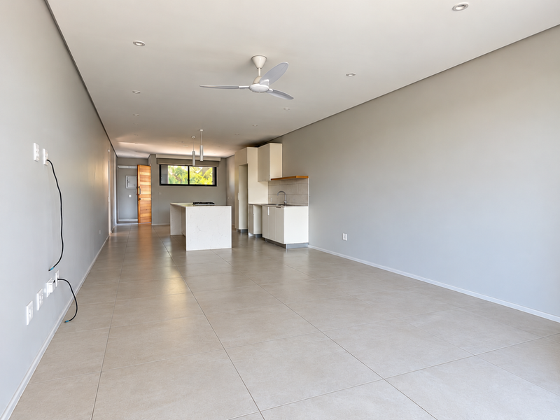 Spacious open-plan living and kitchen area featuring modern tiled flooring, recessed lighting, a central kitchen island, and neutral wall finishes.