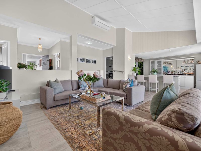 Spacious open-plan living area featuring a modern kitchen with island, neutral finishes, and split-system air conditioning, creating a bright and functional family space.