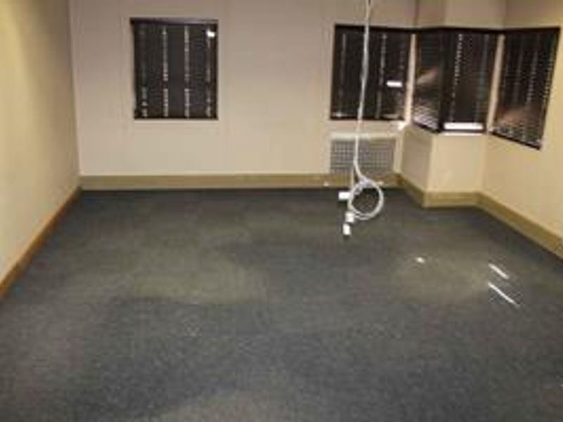 An empty office space featuring carpeted flooring, window blinds, and an integrated HVAC unit, currently requiring minor electrical maintenance.
