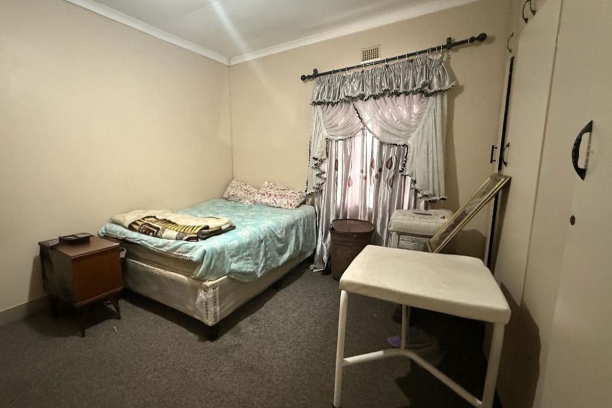 A bedroom featuring built-in cupboards, carpeted flooring, and a window with curtain rails.