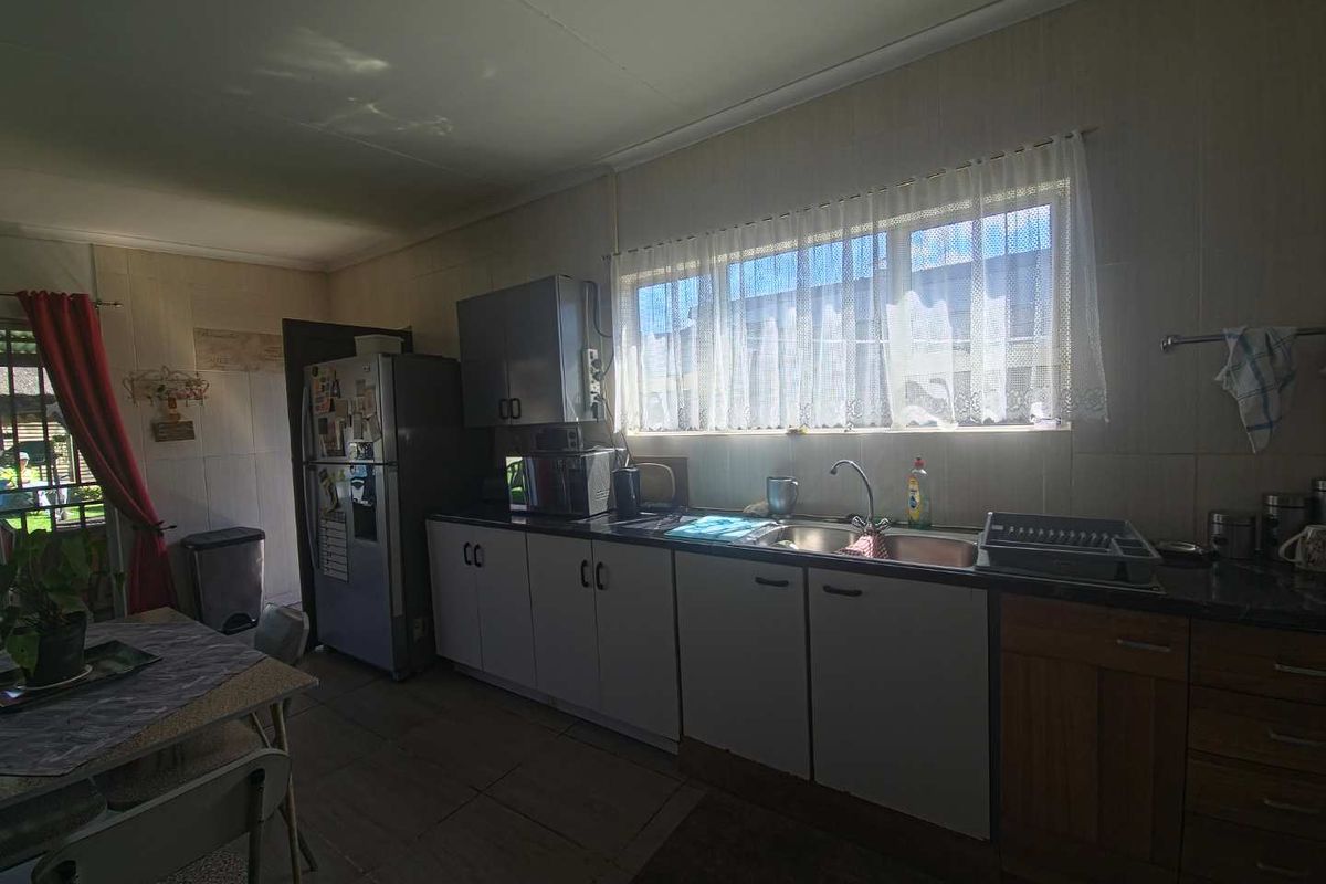 A functional kitchen featuring built-in cabinetry, tiled walls, and a double sink, offering a practical layout with potential for modern updates.