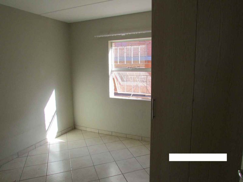 An empty bedroom featuring tiled flooring and a built-in cupboard, offering a neutral space ready for personalization.